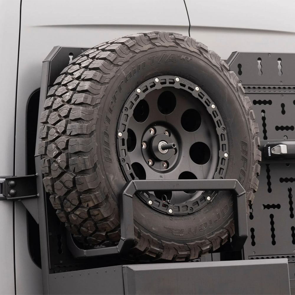 XBull spare wheel carrier holding an off-road tire on a Sprinter rear rack, view 1
