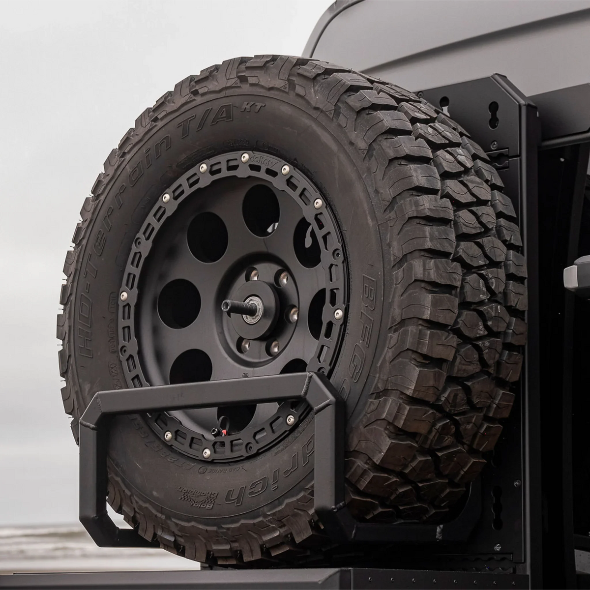 XBull spare wheel carrier holding an off-road tire on a Sprinter rear rack, view 4