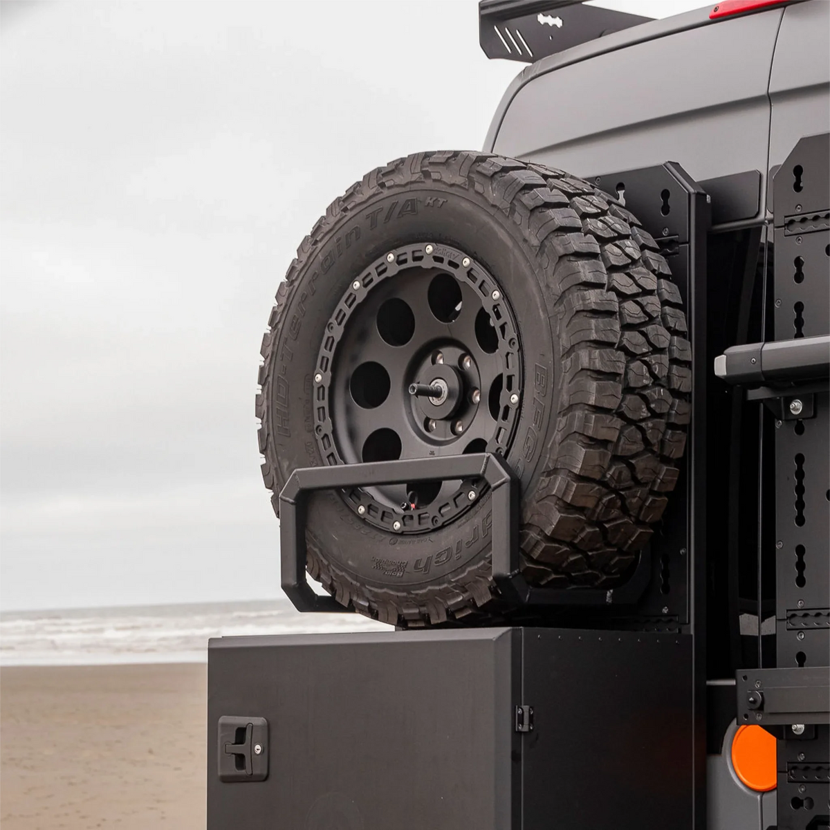 XBull spare wheel carrier holding an off-road tire on a Sprinter rear rack, view 3