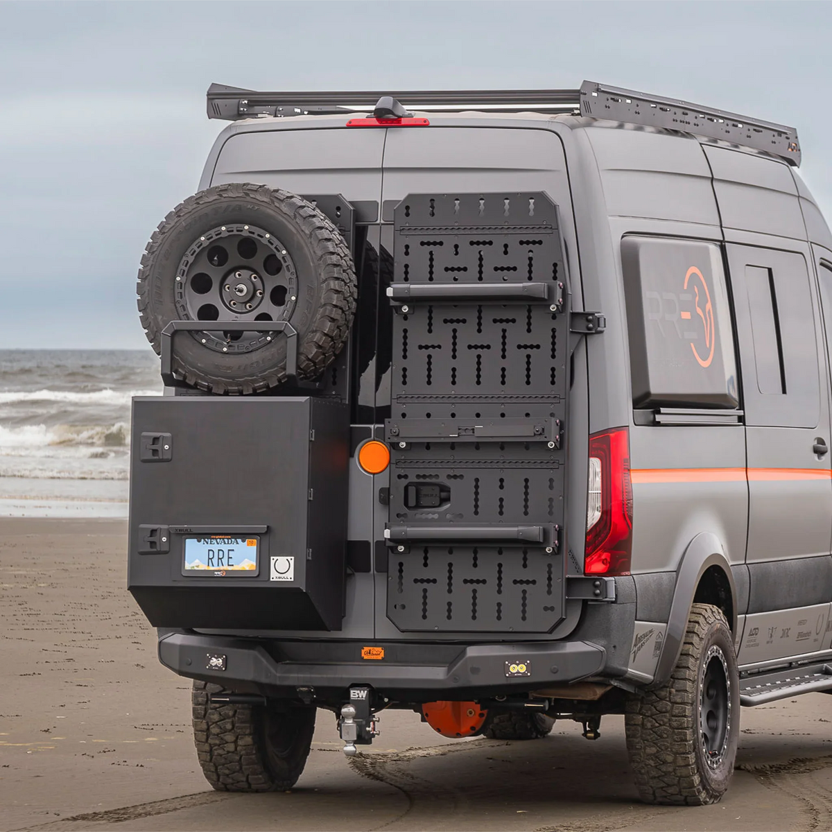 XBull spare wheel carrier holding an off-road tire on a Sprinter rear rack, view 2