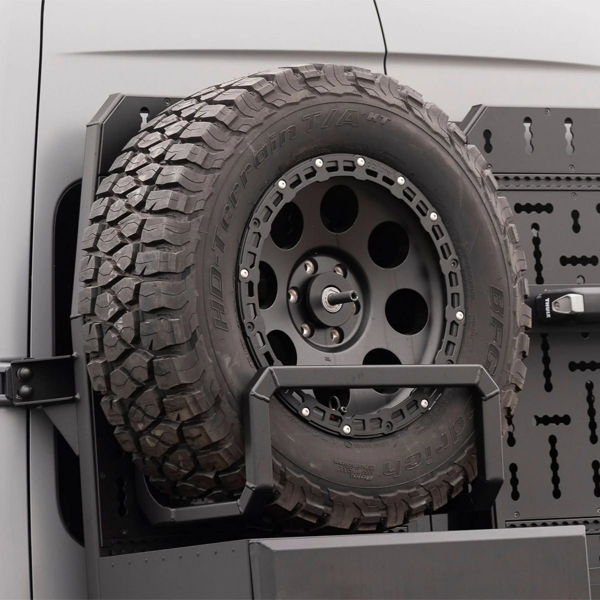 XBull spare wheel carrier holding an off-road tire on a Sprinter rear rack, view 1